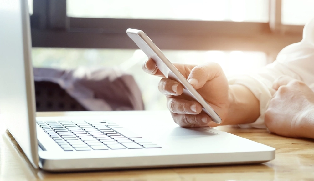 Immagine tematica con uomo che lavora su un computer portatile, e smartphone controllando e leggendo documenti