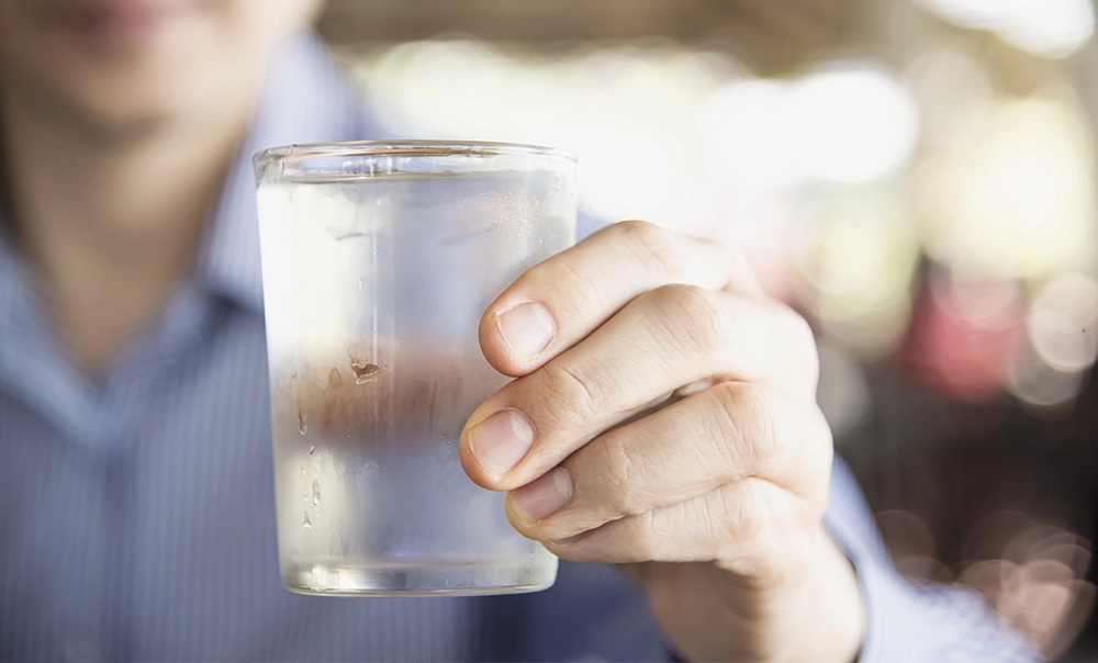 Immagine tematica di uomo in camicia che tiene in mano un bicchiere di fresca acqua