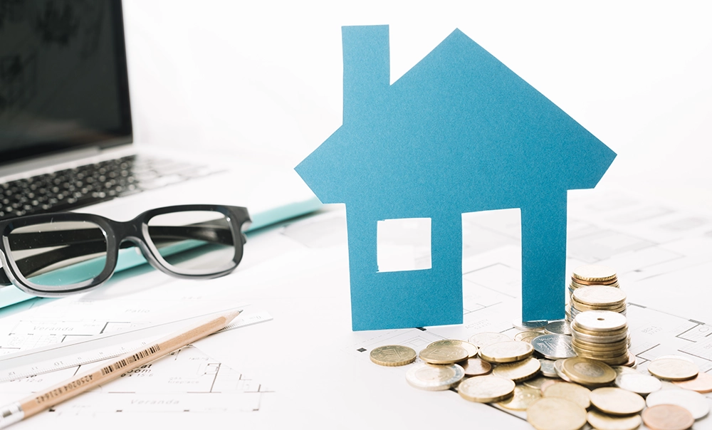 Immagine tematica sulla gestione economica delle spese. Tavolo di lavoro con fogli monete, matita, computer e occhiali da vista.